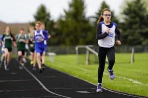 Zosia runs on a track in front of a pack of boys