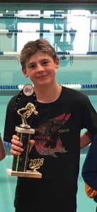 Aidan holds a trophy in front of a pool