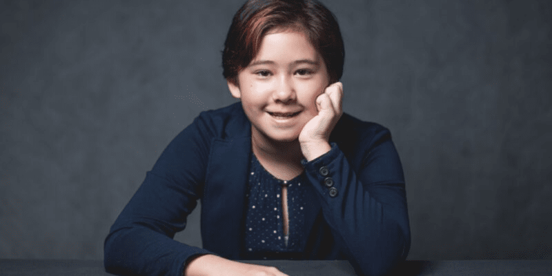 Casey poses in front of a gray background at the Student Conference