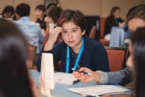 Casey sits at her group's table at the student conference