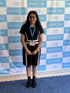 Vidhi poses in front of a Kumon step and repeat at the student conference