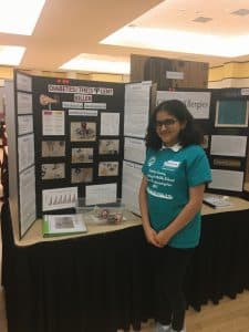 Vidhi poses next to a science fair pster