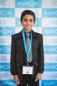 Aaron poses in front of a Kumon backdrop at the student conference