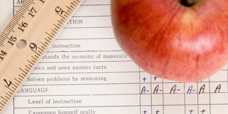 An apple and ruler lay over a report card as a banner image for Tips on Interpreting Report Cards
