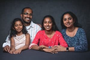 Rishika poses with her family in front of a gray background