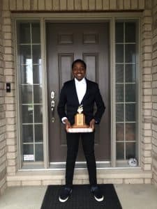 Temi poses with a trophy outside his front door