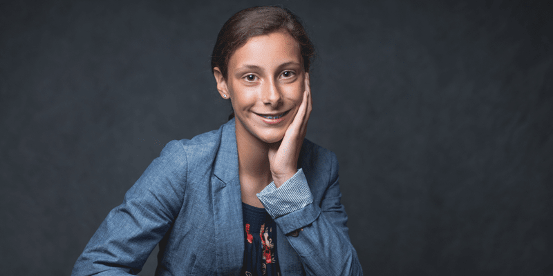Ava poses in front of a grey background