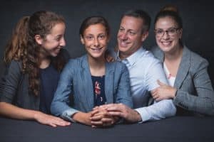 Ava poses with her family in front of a gray background