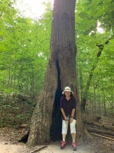 Grace stands against a large tree