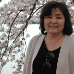 Grace poses in front of a cherry blossom tree