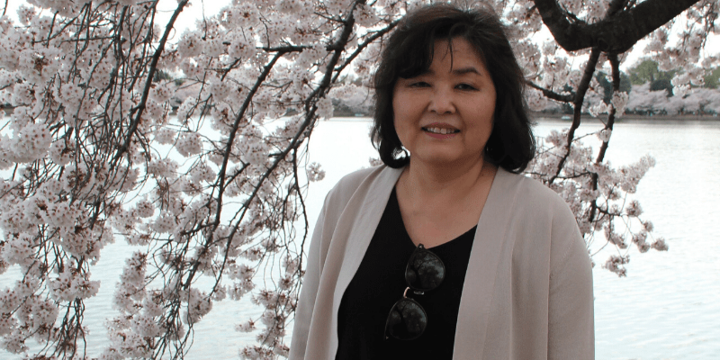 Grace poses in front of a cherry blossom tree