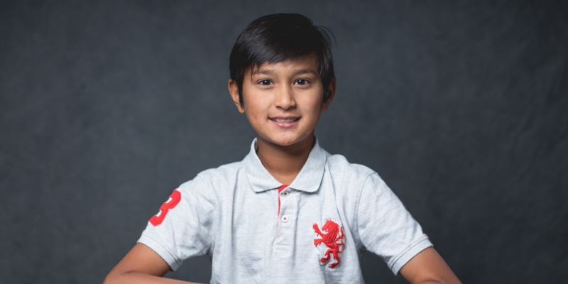 student wearing a white shirt with collar and orange dragon logo on the right of his shirt.
