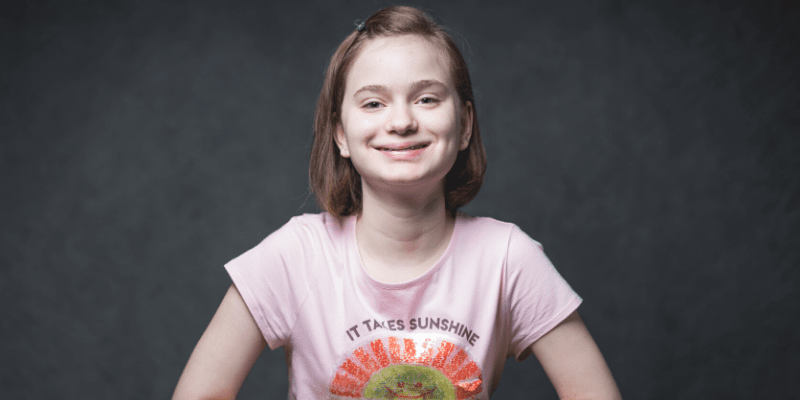 Morgan wearing a pink shirt with a black backdrop.