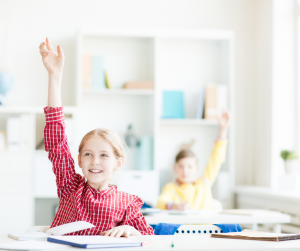Focused on girl with red and white striped hands who is raising her hand while smiling.
