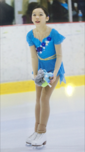 Girl with a blue outfit ice skating on the ice