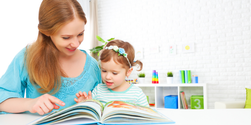 A young girl reads a book to her mother