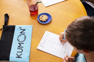 Student doing homework on a kitchen table with kumon pencil case.