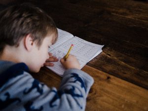 a young boy leaning into his worksheet working out a math problem