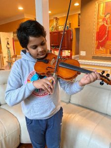 Student playing violin in a living room