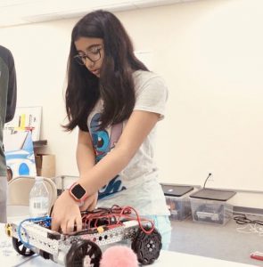 young girl has hand over robot trying to fix it