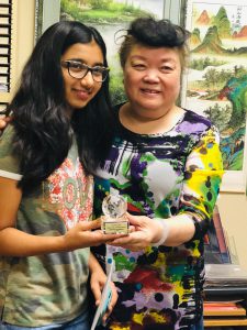 student holding an award with her instructor