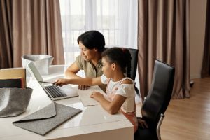 mom and daughter pointing at computer screen for virtual learning