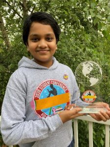 student holding an award outside on the front porch