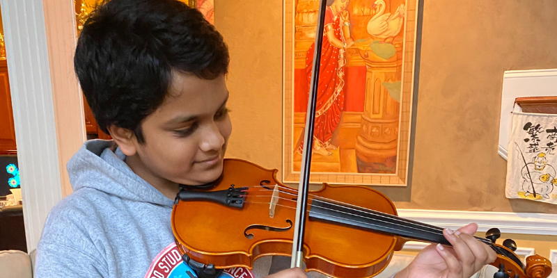 Student plays the violin in front of a painting