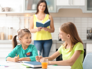 mother stops reading for a moment to see her two daughters talking over homework