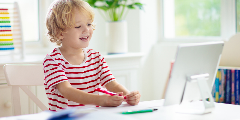 A young boy sits at a computer for remote learning