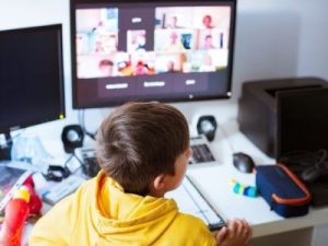 A boy joins a zoom call at his desk for remote school