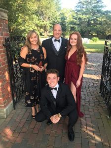 Nicole poses with her husband and two children in black tie attire