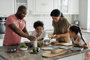 A young family with two children make dinner together in the kitchen