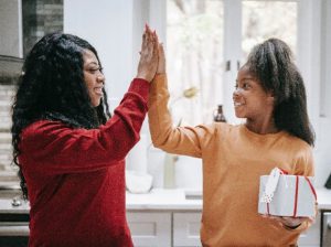 A tween girl high fives her mother