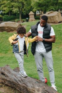 father helping son jump off a log