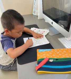Boy infront of screen doing Kumon worksheet