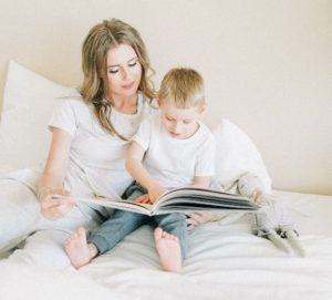 mother reads to her son next to stuffed animal 