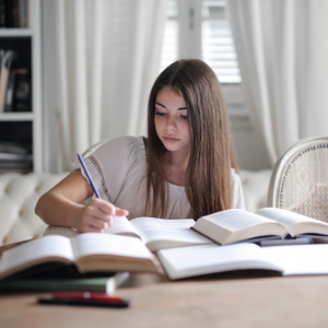 a student studying at home with multiple books open