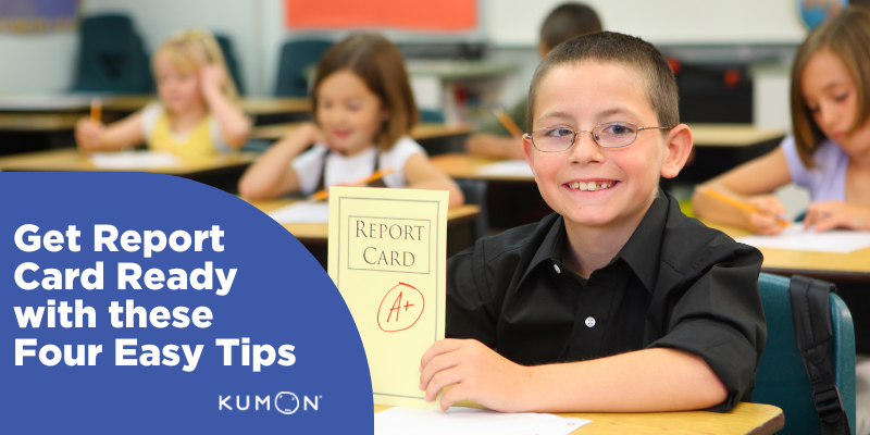 A report card ready child sitting at his desk holding his grades up to the viewer