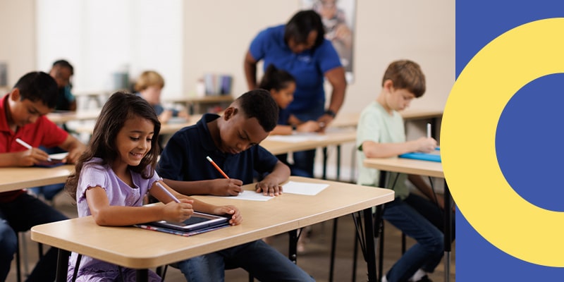 An instructor helps a student while the class practices using both paper and digital worksheets