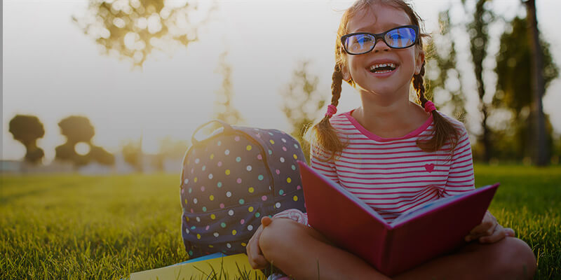 smiling child reading book in the grass
